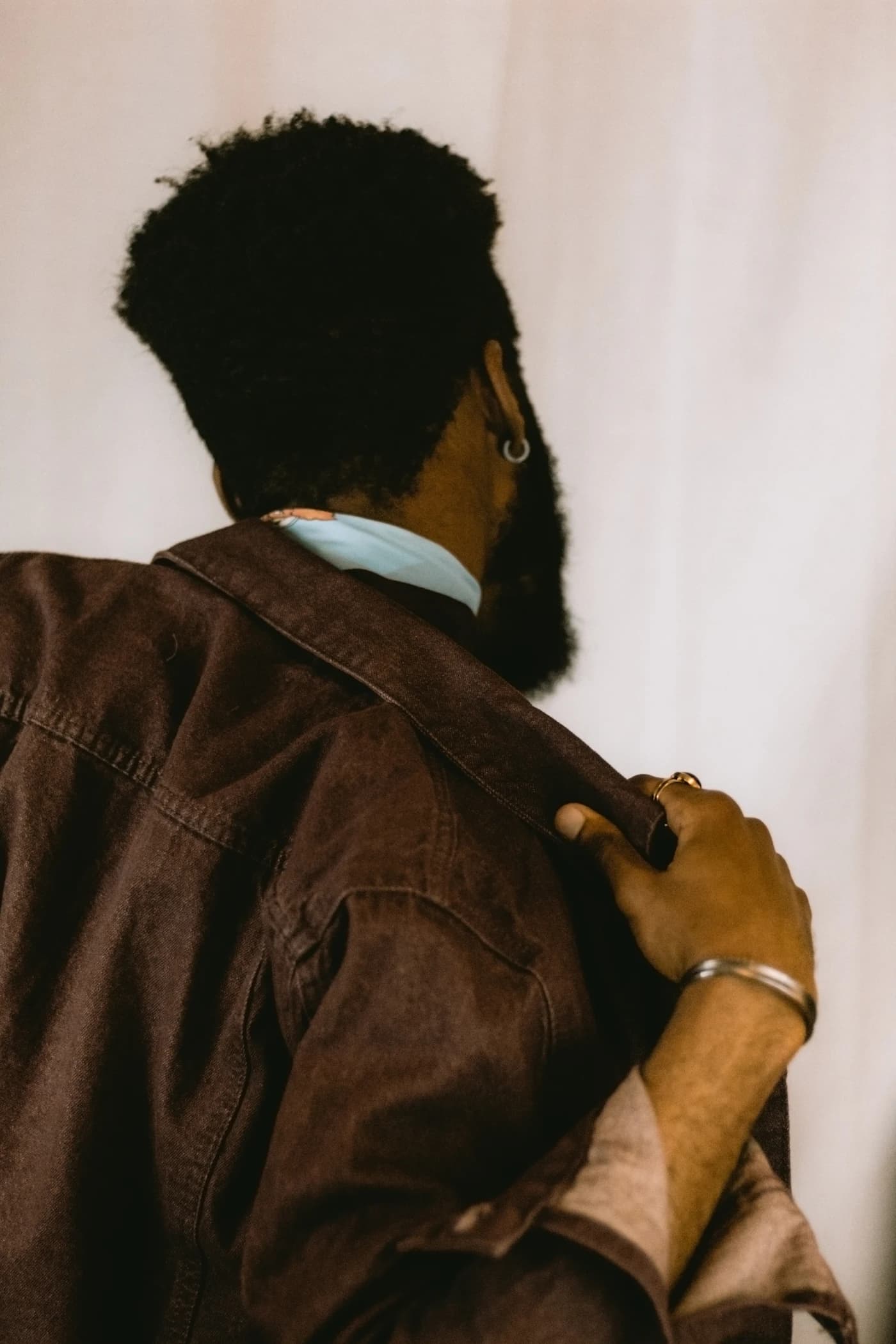 Man in a black leather jacket, low-key editorial portrait.